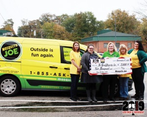 Mosquito Joe representatives pose for a photo with a massive check in front of a yellow and green service van.